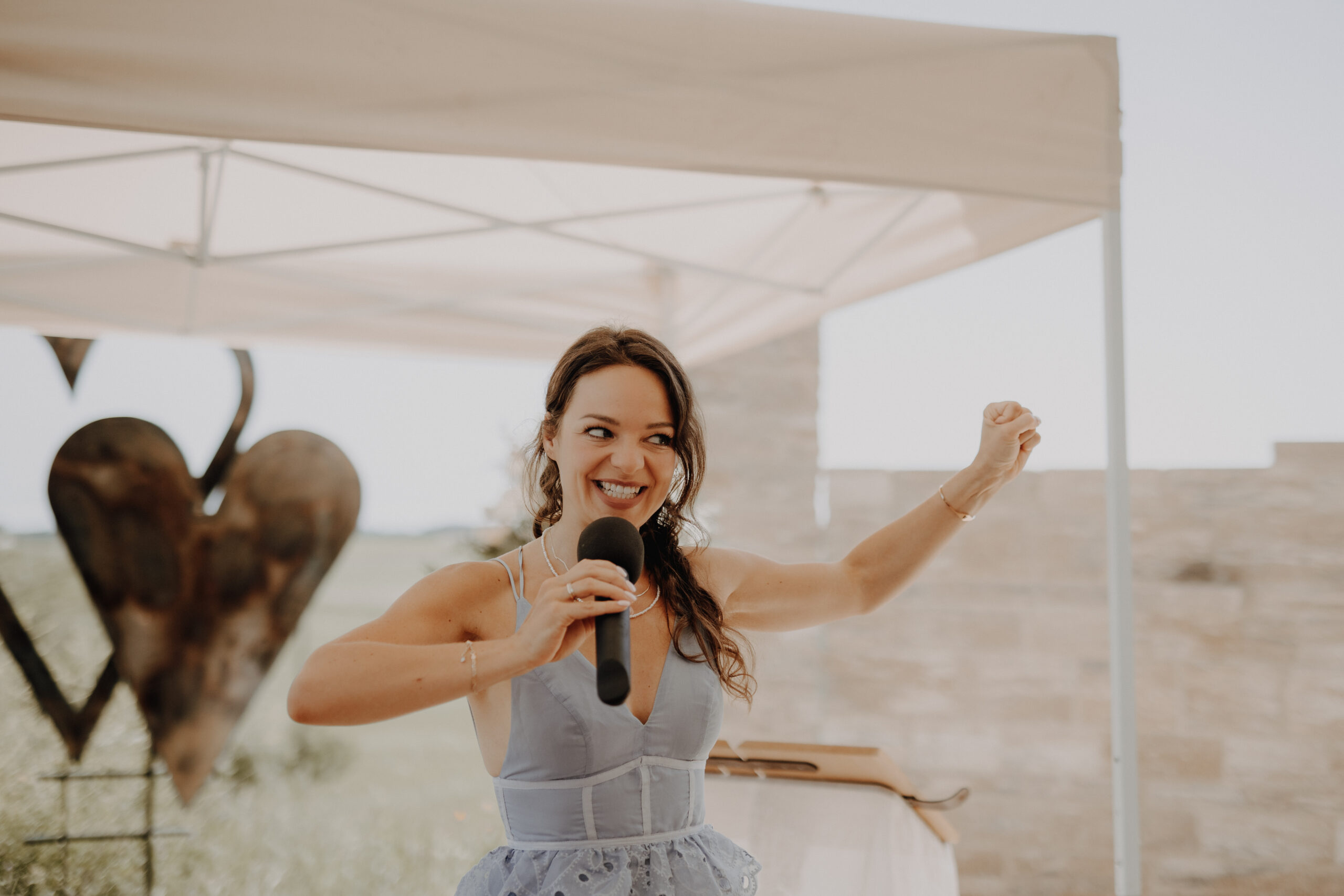 Helene Bauer spricht als freie Rednerin bei einer Hochzeit in Altötting mit Mikrofon und strahlendem Lachen