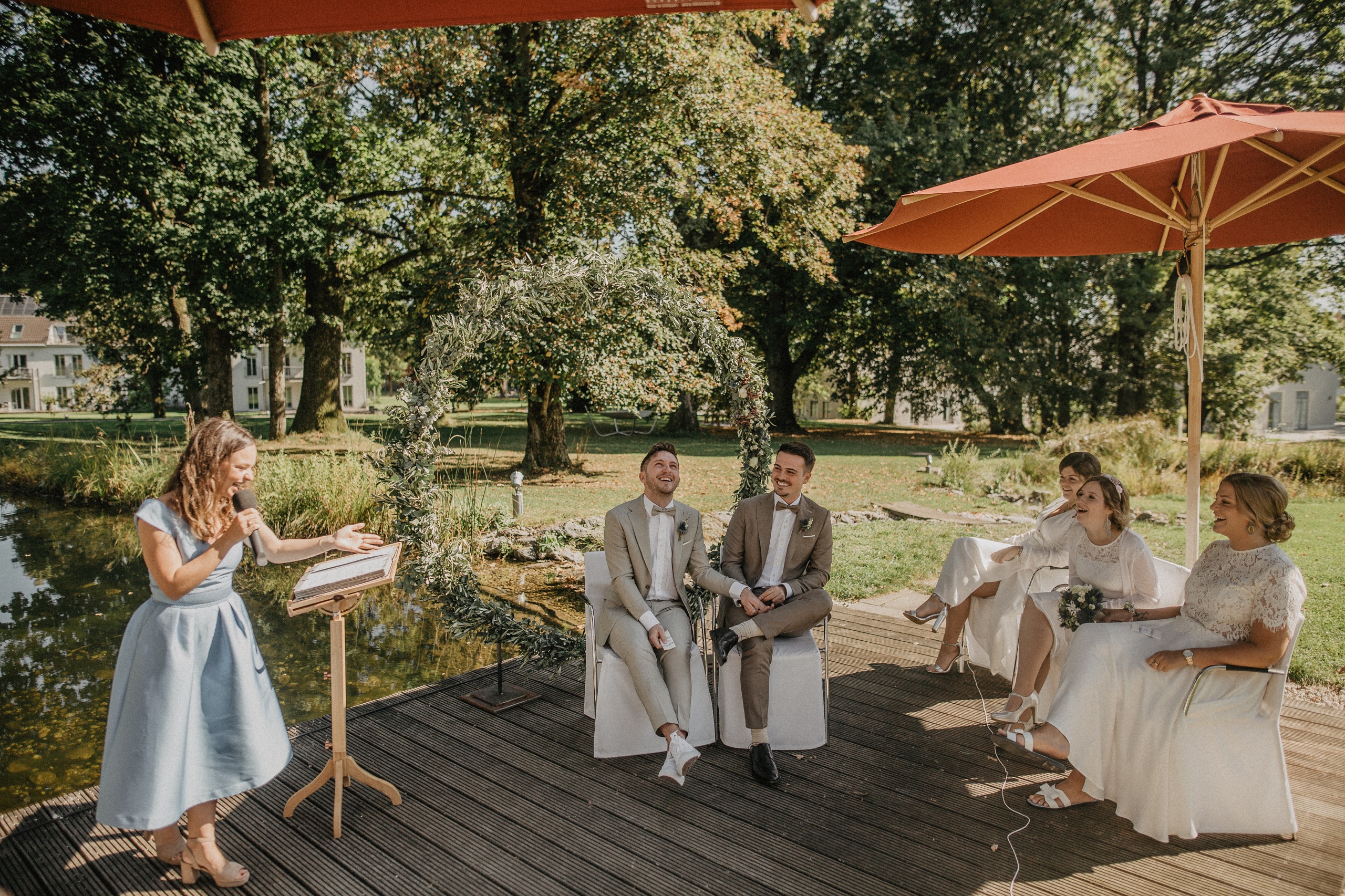 Helene Bauer als freie Rednerin bei einer sommerlichen Hochzeitszeremonie im Grünen mit fröhlichem Brautpaar in Oberbayern