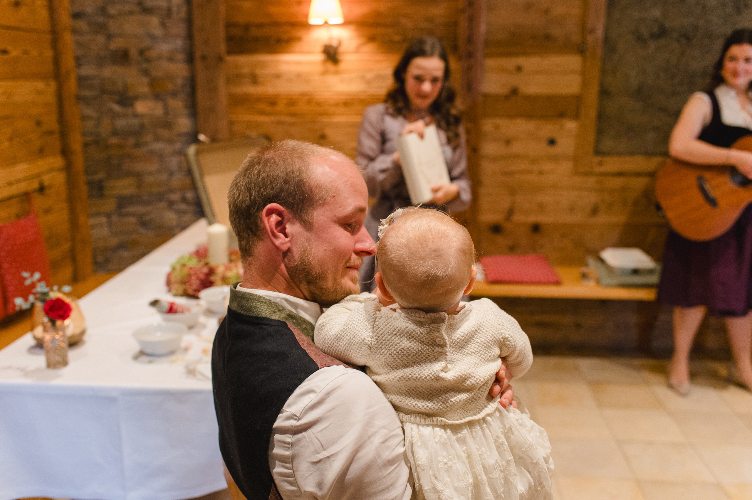 Ein Vater hält sein Baby bei einem Willkommensfest im Gasthaus Forstner Wirt in Rottenburg an der Laaber, im Hintergrund steht Rednerin Helene Bauer mit einem Geschenk in der Hand